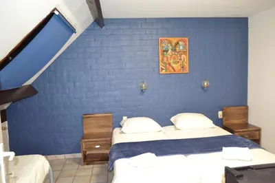 a bedroom with two beds and a blue wall at Hotel Plaza in Lommel