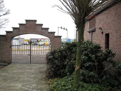 a gate in a brick building with a tree in front of it at Hotel Plaza in Lommel