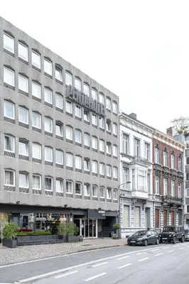 a large gray building with cars parked in front of it at pentahotel Liège in Liège