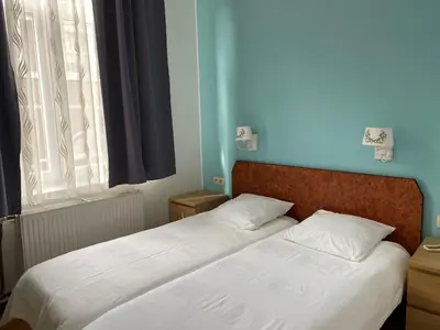 two twin beds in a bedroom with a window at Hôtel Les Acteurs in Liège