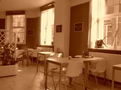 a restaurant with tables and white chairs and windows at Hôtel Les Acteurs in Liège