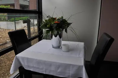 a table with a vase of flowers and a cup on it at Hotel Boomgaard in Lanaken