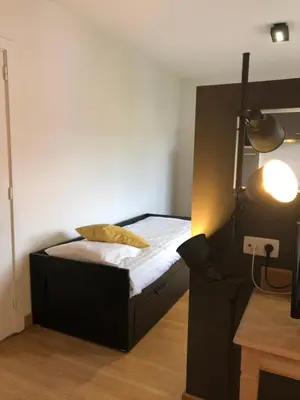 a bedroom with a bed with a yellow pillow on it at Hotel Le Cygne d'Argent in Liège
