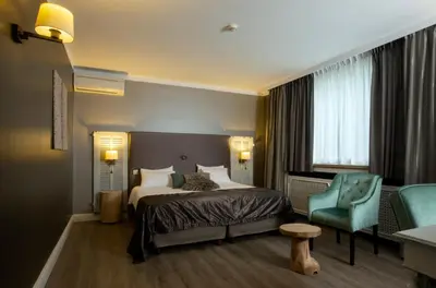 a hotel room with a bed and a blue chair at Hotel Mardaga in As