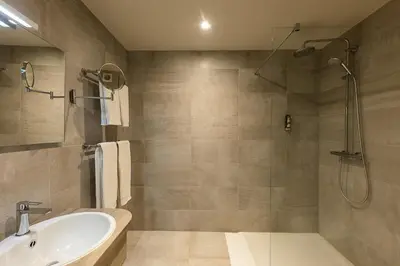 a bathroom with a shower and a tub and a sink at Hotel Malpertuus in Riemst