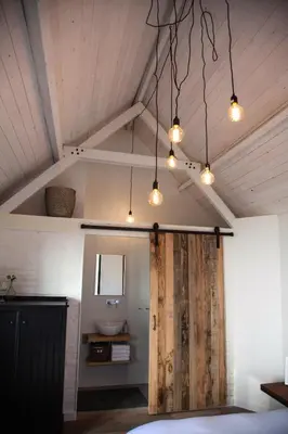 a room with a bathroom with a wooden door and lights at Belle Chique - Maastricht in Lanaken