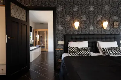 a bedroom with a bed and a bathroom with a tub at B&B Montenakerhof in Riemst