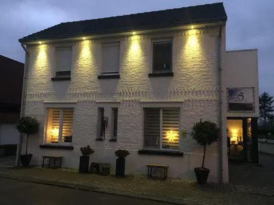 a white building with lights on the side of it at B&B Montenakerhof in Riemst