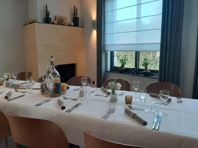 a table with a white table cloth and chairs and a window at Hotel Limburgia in Kanne