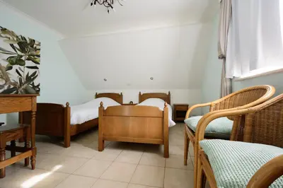 two beds in a room with chairs and a table at Hotel Het Buskruid in Lummen