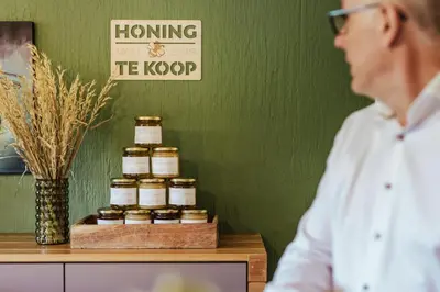 a man standing at a counter with four jars of honey at Hotel Het Buskruid in Lummen