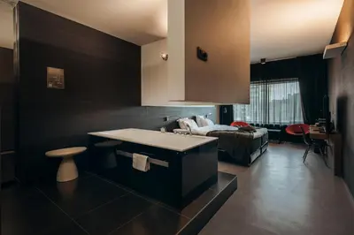 a kitchen with a sink and a living room at Carbon Hotel in Genk