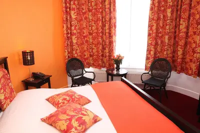 a bedroom with a bed with two chairs and a window at Eurotel in Liège
