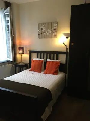 a bedroom with a bed with two orange pillows at Eurotel in Liège