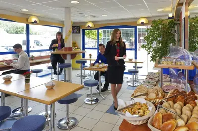 a woman standing in a bakery with a bunch of bread at ibis budget Aachen Raeren Grenze in Raeren