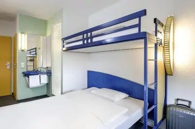 a bedroom with two bunk beds and a suitcase at ibis budget Aachen Raeren Grenze in Raeren
