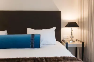 a bed with a blue pillow on top of it at Le Chateau Des Thermes in Chaudfontaine