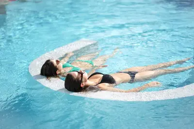 two women are laying on anlatable circle in the water at Le Chateau Des Thermes in Chaudfontaine