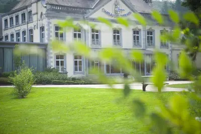a large white building with a lawn in front of it at Le Chateau Des Thermes in Chaudfontaine