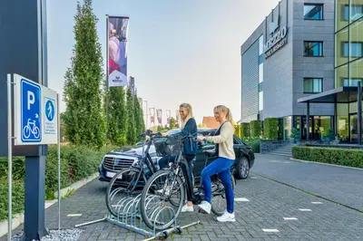 two women are standing next to bikes on a bike rack at Mezzo Hotel & Business in Beringen