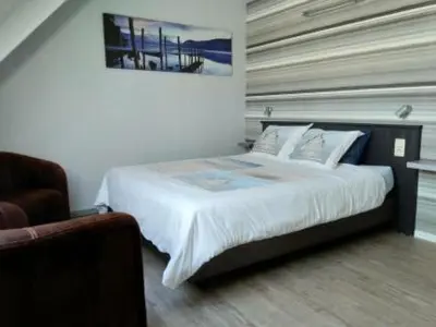 a bedroom with a large bed and a chair at B&B Hoeven Het Gehucht in Overpelt