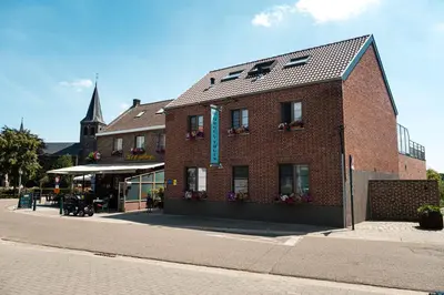 a brick building on a street with a church at B&B Orgel Thuis in Kinrooi