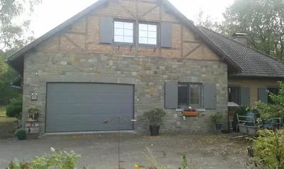 a brick house with a garage and two windows at Villa Lumina in Membach
