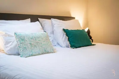 a white bed with white pillows and a green pillow at Smart Bnb - Hotel Battice in Battice