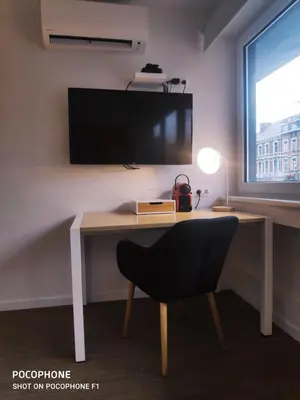 a desk with a chair and a television on a wall at DayNight Sauveniere in Liège