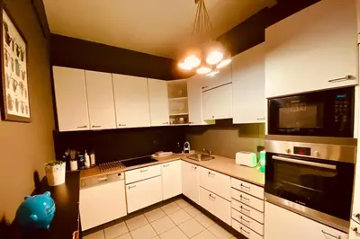 a kitchen with white cabinets and a black microwave at Fenêtre sur le Standard de Liège in Ougrée
