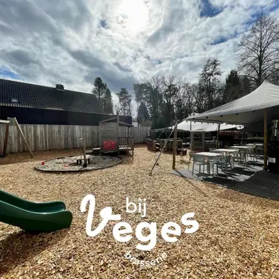 a playground with a green slide and tables and a building at Chalet Relax in Zutendaal