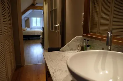 a bathroom with a sink and a hallway with a bedroom at Abeljano in Hasselt