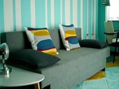 a couch with colorful pillows on it in a living room at Gîte Au26 côté jardin-côté cour in Liège