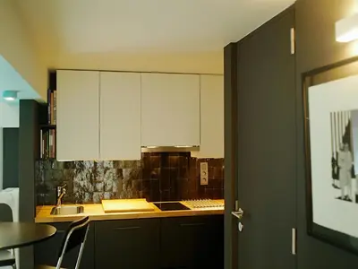 a kitchen with white cabinets and a sink and a table at Gîte Au26 côté jardin-côté cour in Liège