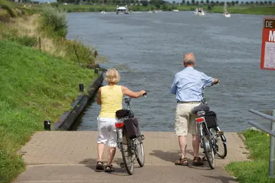 a man and a woman riding bikes along a river at Hotel De Spaenjerd in Kinrooi