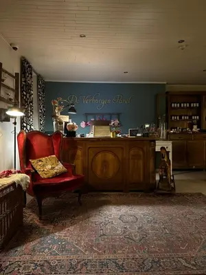 a living room with a red chair and a counter at De Verborgen Parel B&B in Borgloon
