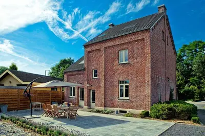 a red brick house with a table and a patio at Vakantiewoning Tivoli in Dilsen-Stokkem