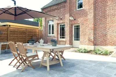 a wooden table with chairs and an umbrella on a patio at Vakantiewoning Tivoli in Dilsen-Stokkem