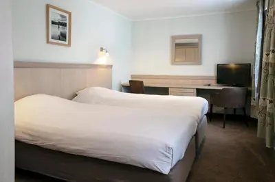 a hotel room with a bed and a desk at La Couronne in Welkenraedt