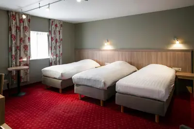 a hotel room with two beds and a red carpet at La Couronne in Welkenraedt