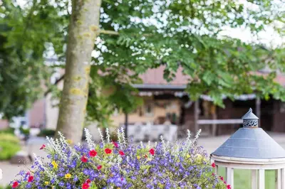 a white gazebo and flowers in front of a building at B&B Domaine Villa Bayard in Kanne