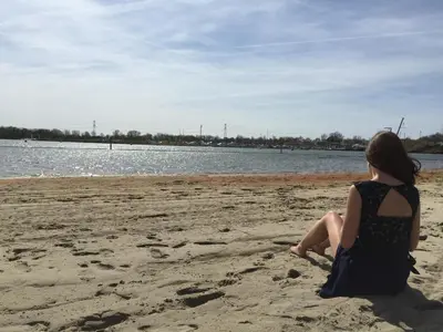 a woman sitting in the sand on the beach at Hotel De Maaskant in Maaseik
