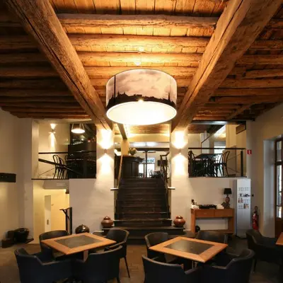 a restaurant with tables and chairs and a staircase at Hotel De Groene Hendrickx in Hasselt