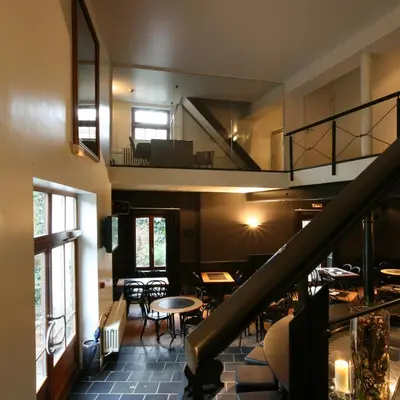a room with a staircase and tables and chairs at Hotel De Groene Hendrickx in Hasselt