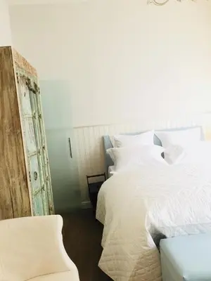 a bedroom with a white bed and a chair at Kirisavan Bed&Breakfast in Borgloon