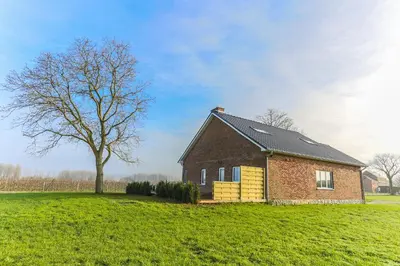 a brick house in a field with a tree at De Oude Katsei in Gingelom