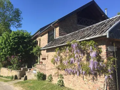 a brick building with purple flowers on it at fermette in Lontzen