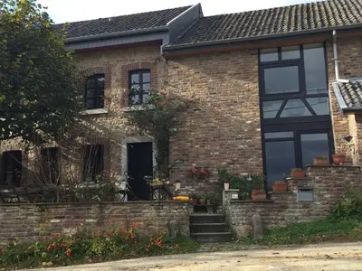 a brick house with black windows at fermette in Lontzen