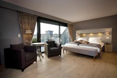 a bedroom with a bed and a couch and a chair at Tuinhotel in Lommel