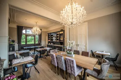 a dining room with tables and chairs and a chandelier at Villa Copis in Borgloon
